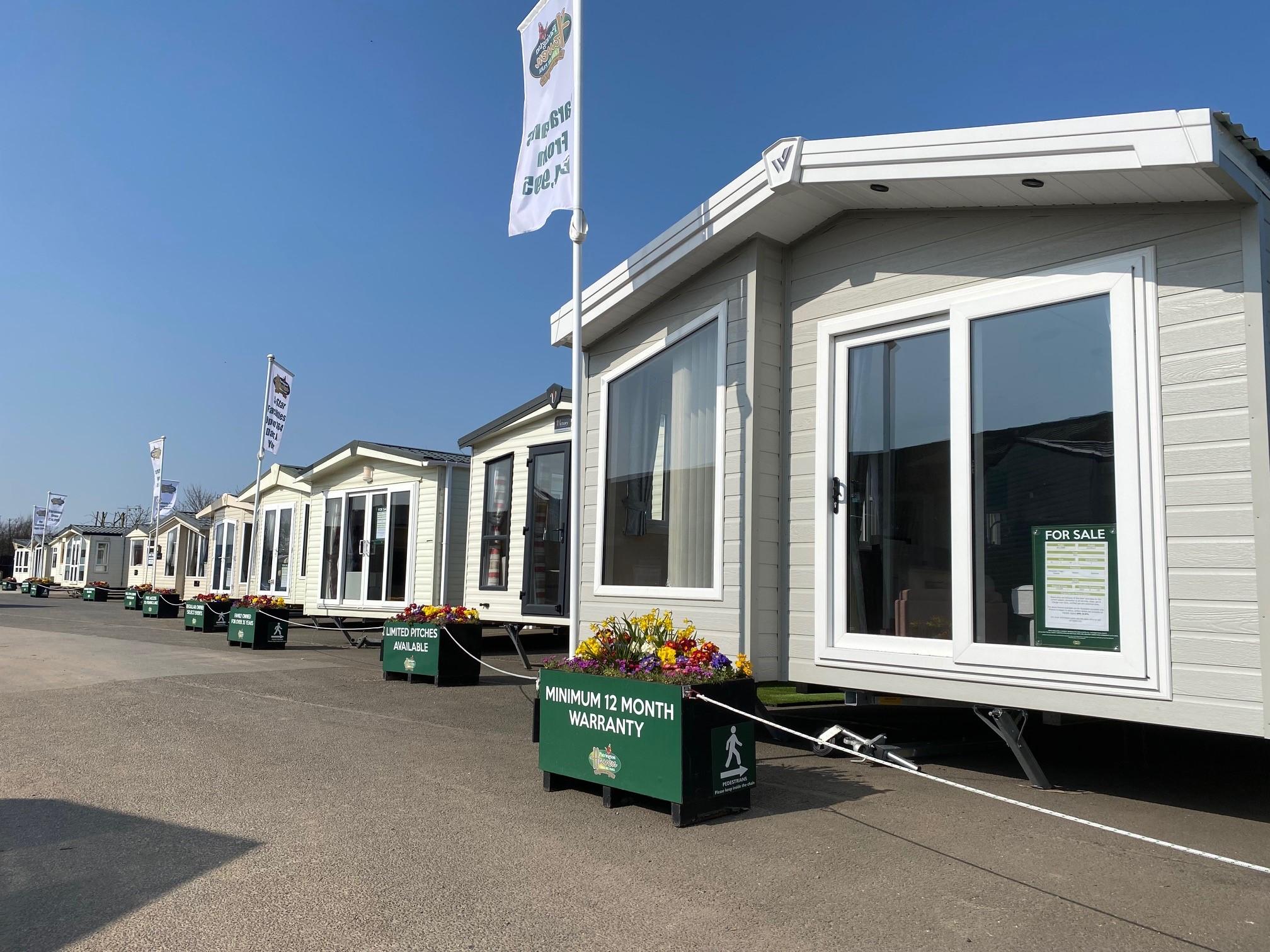 A static caravan with a spacious decking area is nestled in the lush green countryside, offering a peaceful retreat for potential owners. This new caravan is perfect for those looking to discover caravan ownership in a beautiful location.