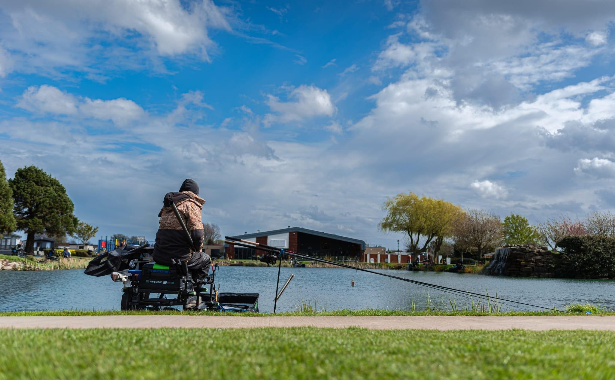 A person is fishing peacefully by a serene lake at sunrise, surrounded by a gentle mist hovering over the water, creating a tranquil atmosphere perfect for relaxation and family fun. This picturesque scene captures the essence of the great outdoors, ideal for holiday park visitors in East Yorkshire looking to unwind and explore local attractions.