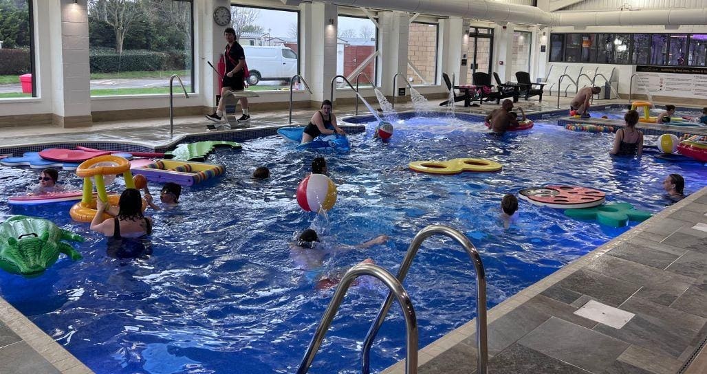 A joyful family is playing together in an indoor swimming pool, splashing water and enjoying quality time with their loved ones. This scene captures the essence of family fun at a holiday park, perfect for creating lasting memories during their caravan holidays in East Yorkshire.